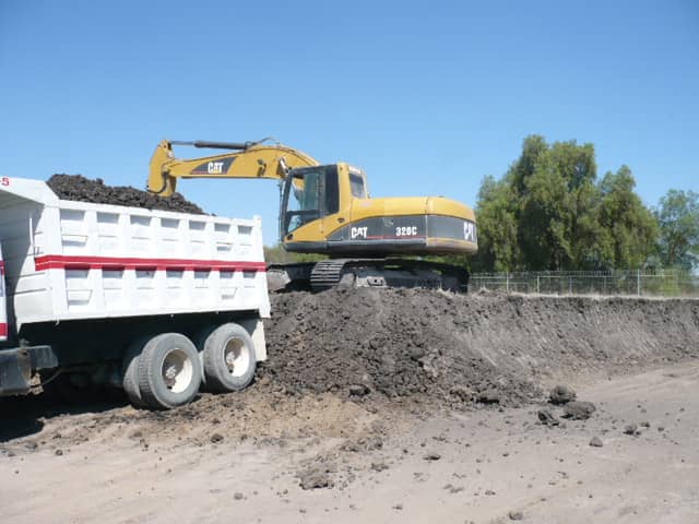 Excavadora Caterpillar 320 cargando material a camión de volteo