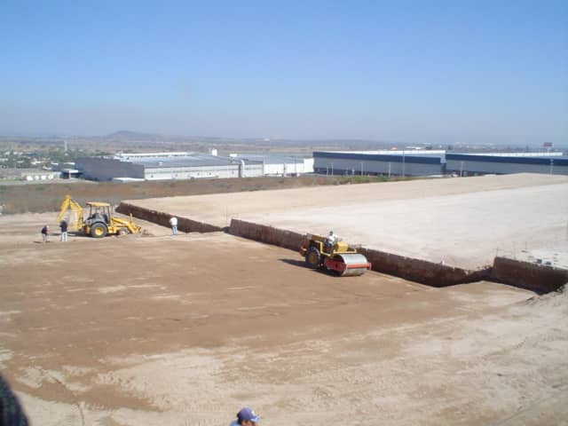 Plataforma de cimentación para nave industrial con retroexcavadora y vibrocompactador